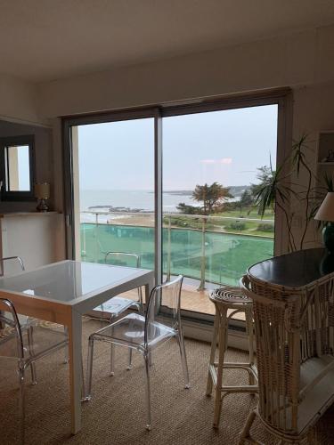 - un salon avec une table, des chaises et une grande fenêtre dans l'établissement Appartement, à Préfailles