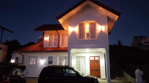 een wit huis met een auto ervoor geparkeerd bij Thuring's Holiday Bungalow in Nuwara Eliya