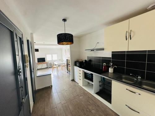 une cuisine avec des armoires en noir et blanc et une table dans l'établissement Grand T2 50m2 Narbonne centre, vue sur cathédrale, à Narbonne