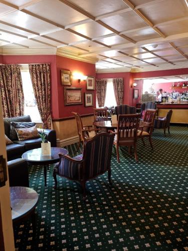 a lobby with chairs and tables and a bar at Passford House Hotel in Lymington