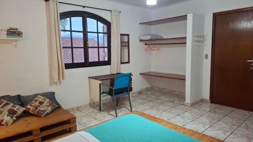 a room with a couch and a desk and a window at O Paraiso é Aqui ! Casa de Hóspedes in Ubatuba