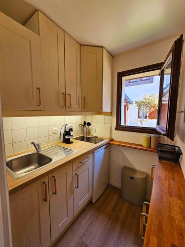 une cuisine avec des armoires blanches, un évier et une fenêtre dans l'établissement Cottage Family, à Blonville-sur-Mer