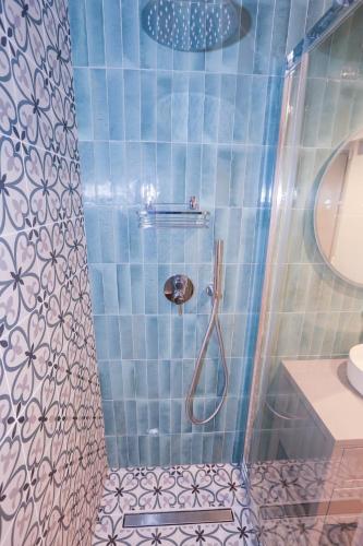 La salle de bains est pourvue de carrelage bleu, d'une douche et d'un lavabo. dans l'établissement Fabulous Green 2-room apartment in the center of Grasse, à Grasse