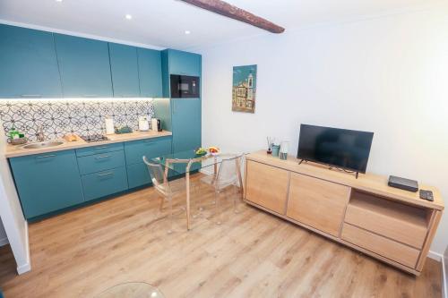 une cuisine avec des armoires bleues et une table en verre dans l'établissement Fabulous Green 2-room apartment in the center of Grasse, à Grasse
