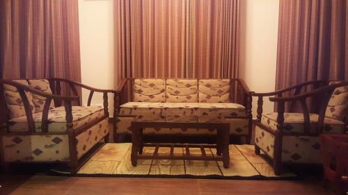 two chairs and a bench in a room with curtains at Thuring's Holiday Bungalow in Nuwara Eliya