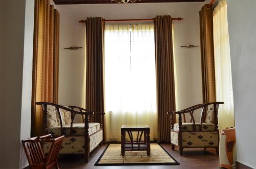 a room with two chairs and a large window at Thuring's Holiday Bungalow in Nuwara Eliya