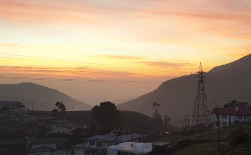 a sunset over a city with mountains in the background at Thuring's Holiday Bungalow in Nuwara Eliya