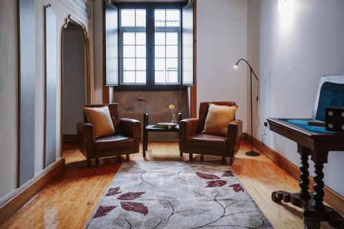 a room with two chairs and a table and a piano at Boanova Guesthouse Convento Cucujães in Oliveira de Azemeis