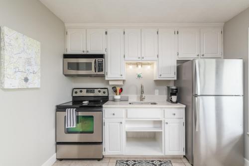 a kitchen with white cabinets and a stainless steel refrigerator at Beaufort's Blue Heron Hideaway on Battery Creek in Beaufort