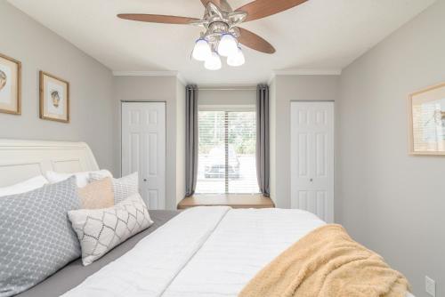 a bedroom with a white bed with a ceiling fan at Beaufort's Blue Heron Hideaway on Battery Creek in Beaufort