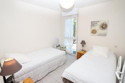 une chambre avec deux lits et une fenêtre dans l'établissement St Cyprien appart 3etoiles avec belle terrasse, à Saint-Cyprien