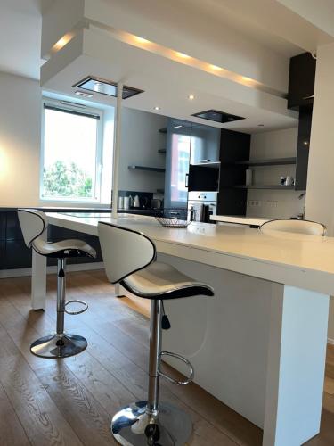une cuisine avec un grand comptoir blanc et des tabourets dans l'établissement Artimon By Les Ambassadeurs, à Saint-Malo