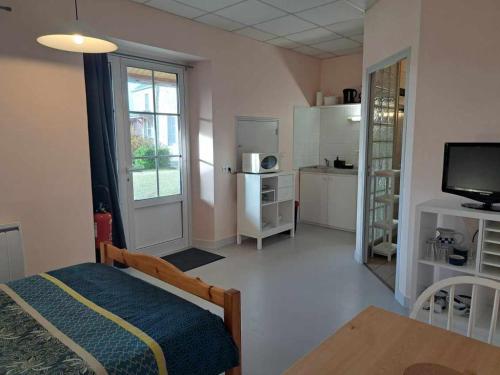 Cette chambre comprend un lit, une table et une télévision. dans l'établissement Le Lerry aux Pierres Bleues, à Surtainville