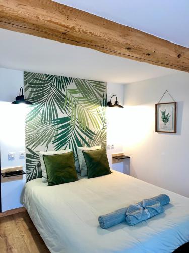 - une chambre avec un grand lit blanc et du papier peint tropical dans l'établissement Le Havre d Adrien, à Illiat
