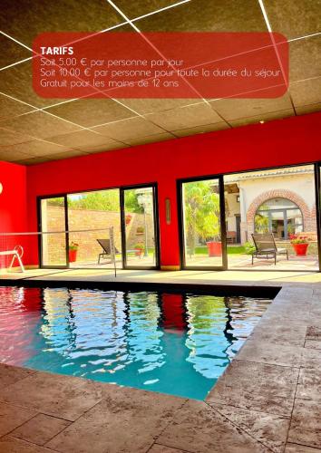 - une piscine dans un bâtiment doté d'un mur rouge dans l'établissement Le Havre d Adrien, à Illiat