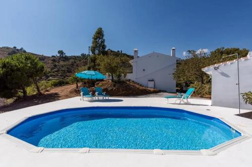 a swimming pool with two chairs and an umbrella at Charming Villa in Competa with Private Pool in Cómpeta