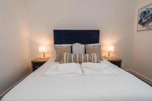 a bedroom with a large white bed with two lamps at Thornhill House Apartments by VICHY in Wakefield