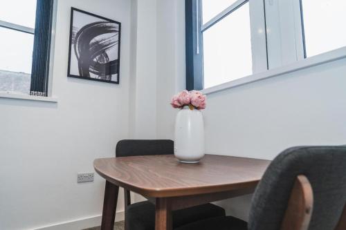 a vase with flowers sitting on a wooden table at Thornhill House Apartments by VICHY in Wakefield