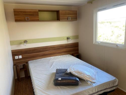 une chambre avec un lit avec une fenêtre et un sac dessus dans l'établissement Mobil home pour 6, près de la mer, dans un camping 4 étoiles à 20min de Montpellier., à Vic-la-Gardiole
