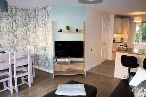a living room with a flat screen tv and a table at 3 bedroom town house with cwtch hobbit play room in Ebbw Vale