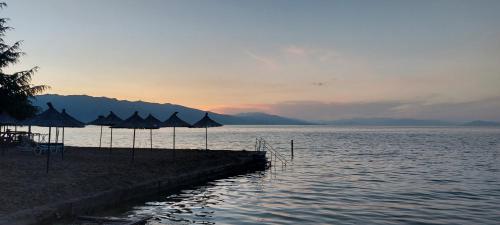 a group of umbrellas on a beach next to the water at Villa Nathanael Cozy Rooms with Balcony in Pogradec