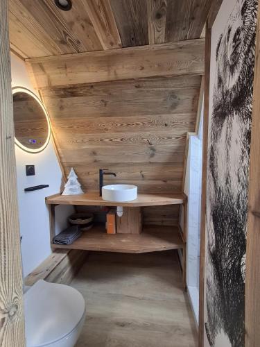 La salle de bains est pourvue d'un mur en bois, d'un lavabo et de toilettes. dans l'établissement Chalet Cosy Cabane avec vue lac, aux Angles