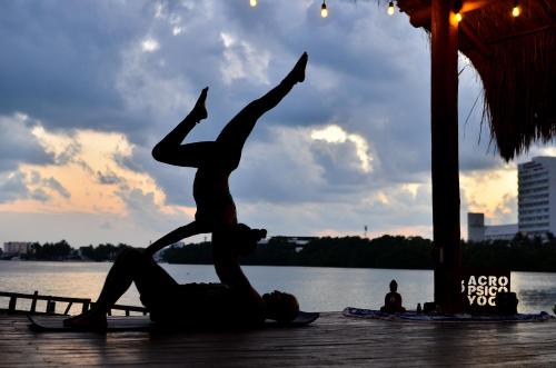 two people doing yoga on a dock near the water at Nílu Cancun Zona Hotelera by Selina in Cancún