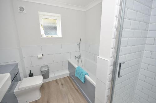 a white bathroom with a toilet and a sink at Wherrymere in Horning