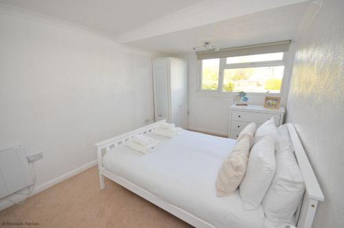 a white bedroom with a white bed and a window at The Moorings in Wroxham