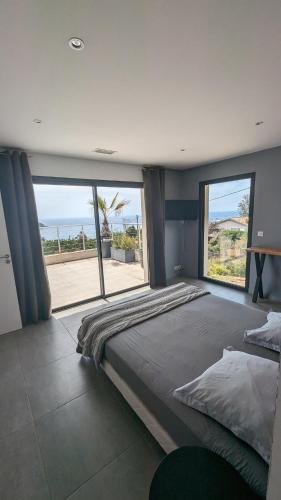 - une grande chambre avec un grand lit et de grandes fenêtres dans l'établissement Superbe villa moderne sur Capo di Muro, à Coti-Chiavari