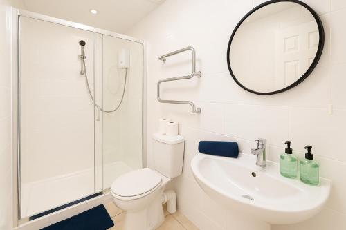 a bathroom with a toilet and a sink and a mirror at 6 Person Apartment in City Centre in Cardiff