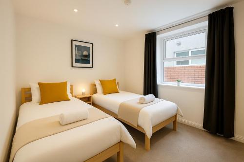 two beds in a room with a window at 6 Person Apartment in City Centre in Cardiff