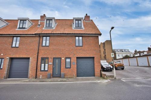 a brick house with two garage doors in a parking lot at Pebble Beach by the Sea in Deal