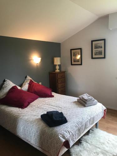 une chambre avec un lit avec des oreillers rouges dans l'établissement Villa Eléno, au cœur de la région des lacs du Jura, à Meussia