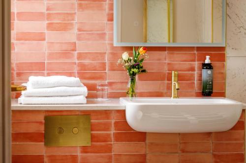 a bathroom with a sink and a vase of flowers at Club House Hotel Kilkenny in Kilkenny