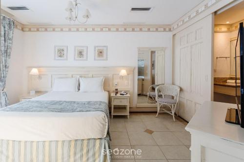 a bedroom with a white bed and a desk and a chair at Studios frente ao mar no IL Campanario Resort ILCTOP in Florianópolis
