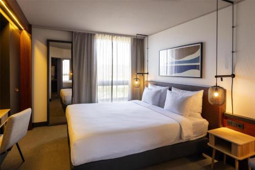 a hotel room with a large white bed and a table at Scandic Nürnberg Central in Nürnberg