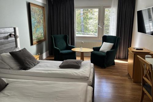 a bedroom with a bed and two chairs and a table at Hotel Ullinge in Eksjö