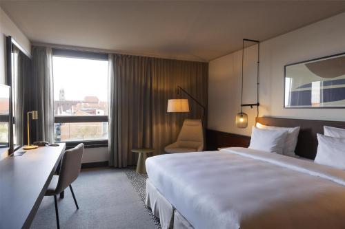 a hotel room with a bed and a desk and a window at Scandic Nürnberg Central in Nürnberg