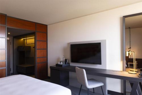 a bedroom with a bed and a desk with a television at Scandic Nürnberg Central in Nürnberg