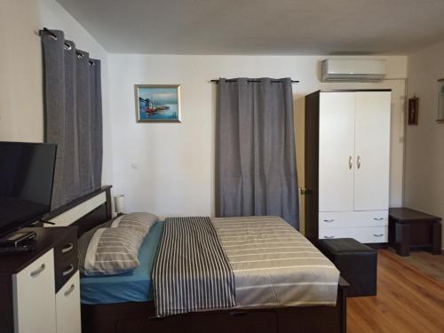 a bedroom with a bed and a flat screen tv at Plitvice Studio Apartments in Rudanovac