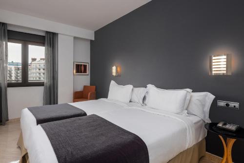 a hotel room with a large white bed and a window at Hotel Spa Cádiz Plaza in Cádiz