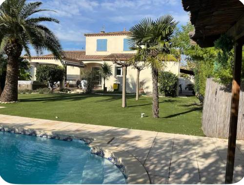 une maison avec des palmiers et une piscine dans l'établissement Villa avec piscine, à Gallargues-le-Montueux