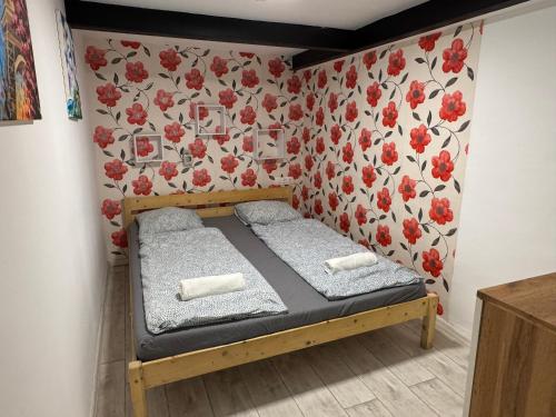 ブダペストにあるStylish Apartment in Central Budapest - Perfect for Couples, Groups and Sightseersの壁に赤い花が飾られた部屋にある小さなベッド
