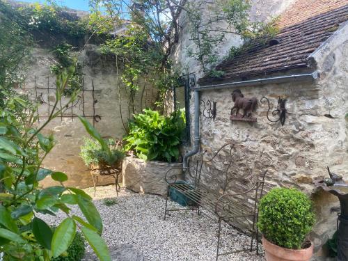 a garden with a stone building with a statue of a horse on the wall at Maison des Roses in Fontaine-Chaâlis