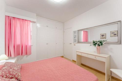 a bedroom with a pink bed and a desk at Spacious apartment with the private terrace in Arona