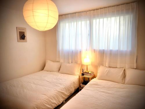 a bedroom with two beds and a lamp and a window at Shym Stay Suwon Haenggung in Suwon