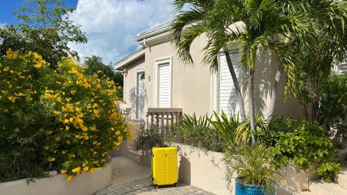 Una casa con un bote de basura amarillo en un jardín. en King Bedroom Suite at ParadiseOneVilla Turks and Caicos Islands, en Providenciales