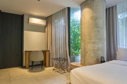a bedroom with a bed and a chair and a window at Seissta Medellín in Medellín