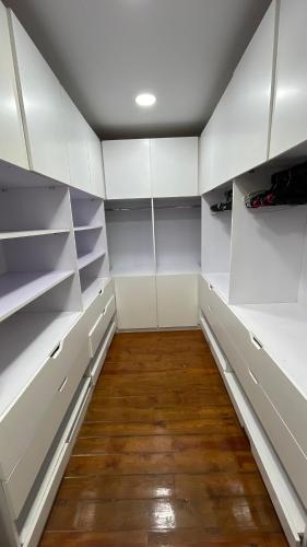 a walk in closet with white cabinets and wood floors at الشيخ زايد بيفرلي هيلز كمبوند اليجريا in 6th Of October